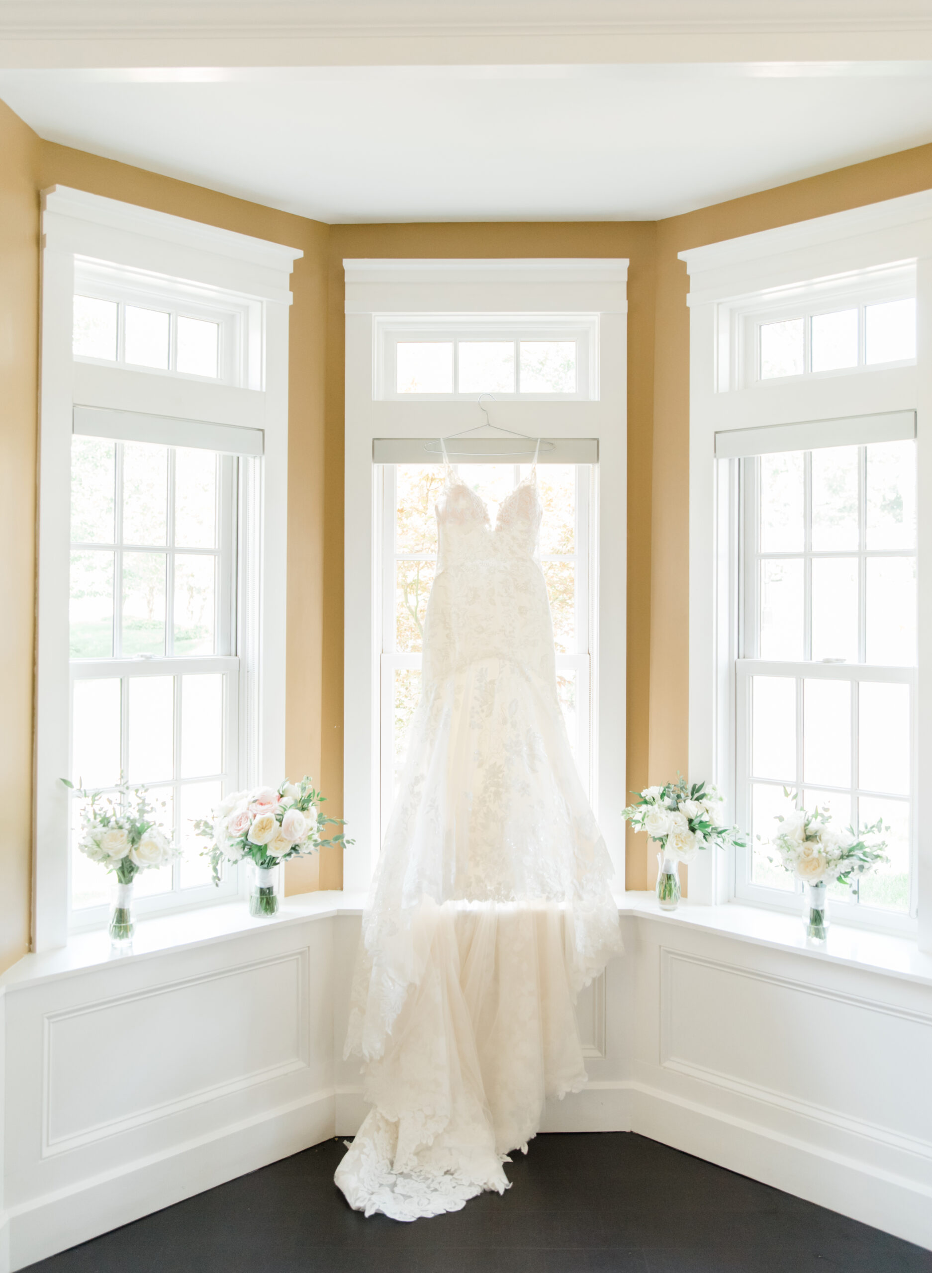 A pretty wedding dress hanging in a window.